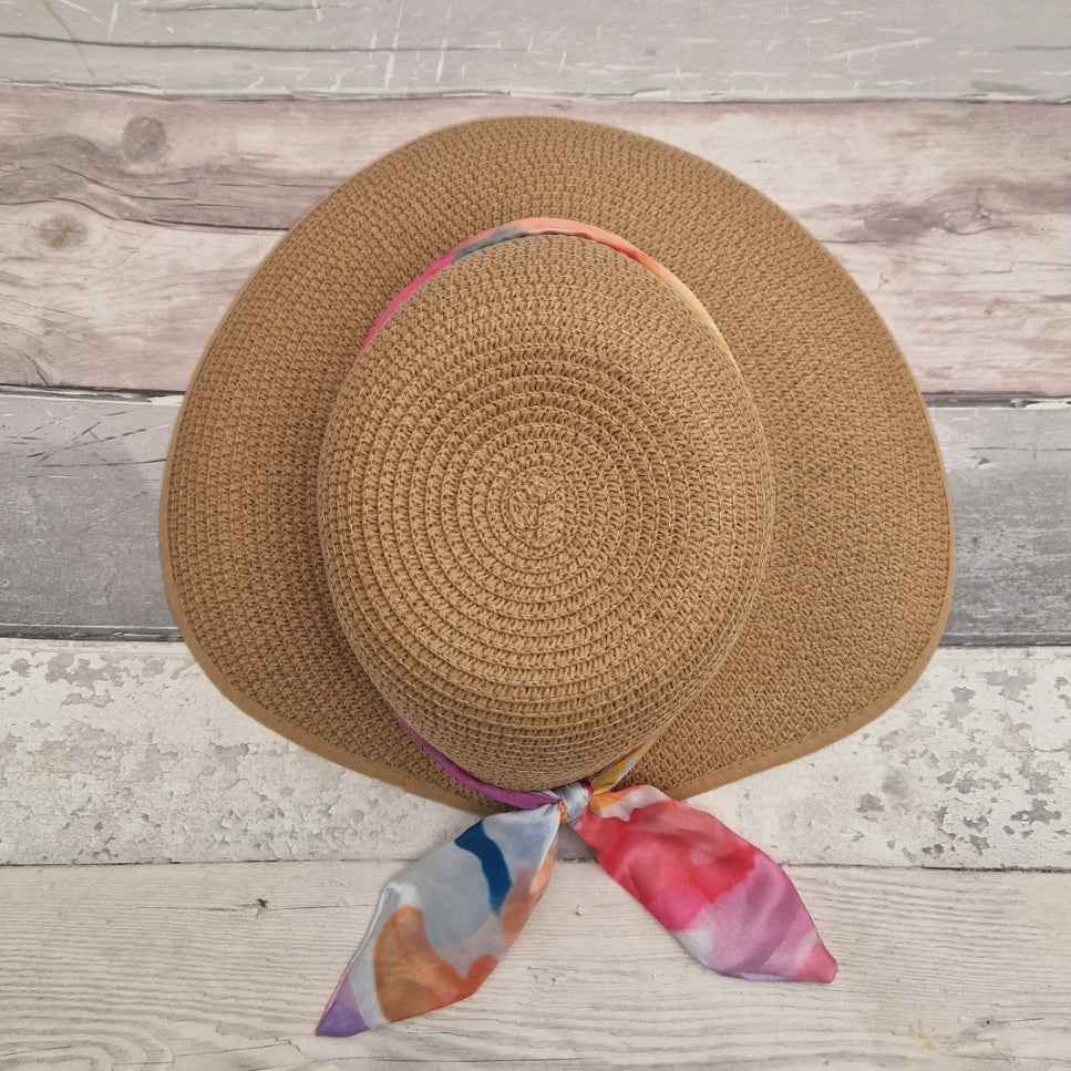 A beige coloured backless bonnet with a rainbow coloured ribbon band shown from above.