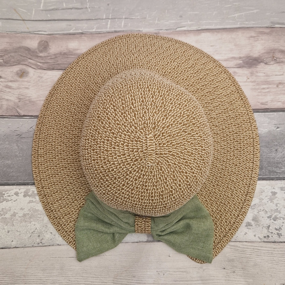 A backless bonnet in natural biscuit colour, finished with a large green bow across the back.