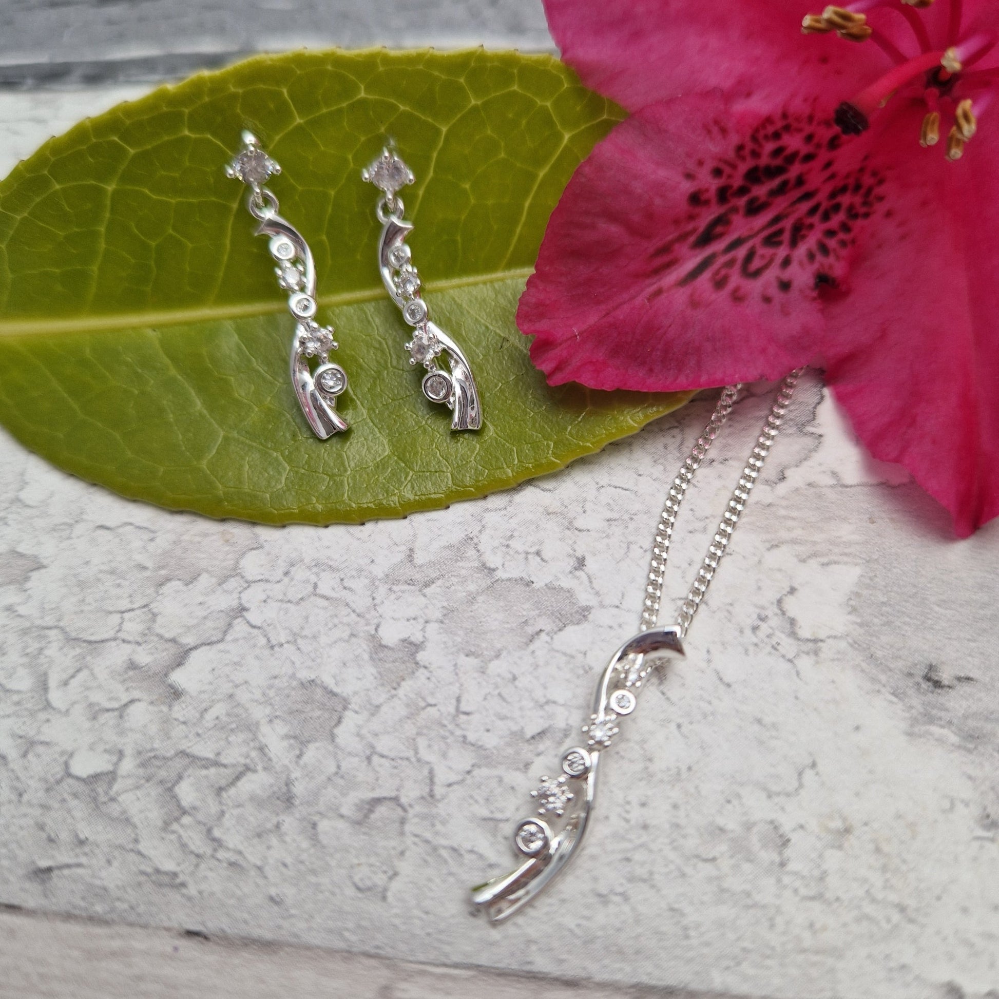 Silver plated necklace and earrings with a rippling sparkle pendant decorated with diamante crystals.