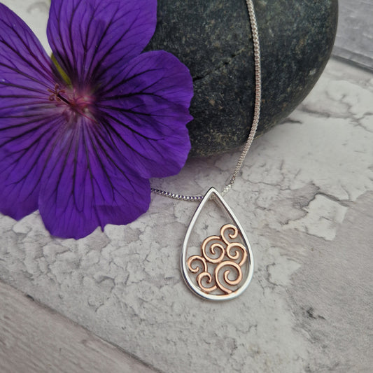 Oval shaped pendant necklace inset with ocean waves in rose gold.