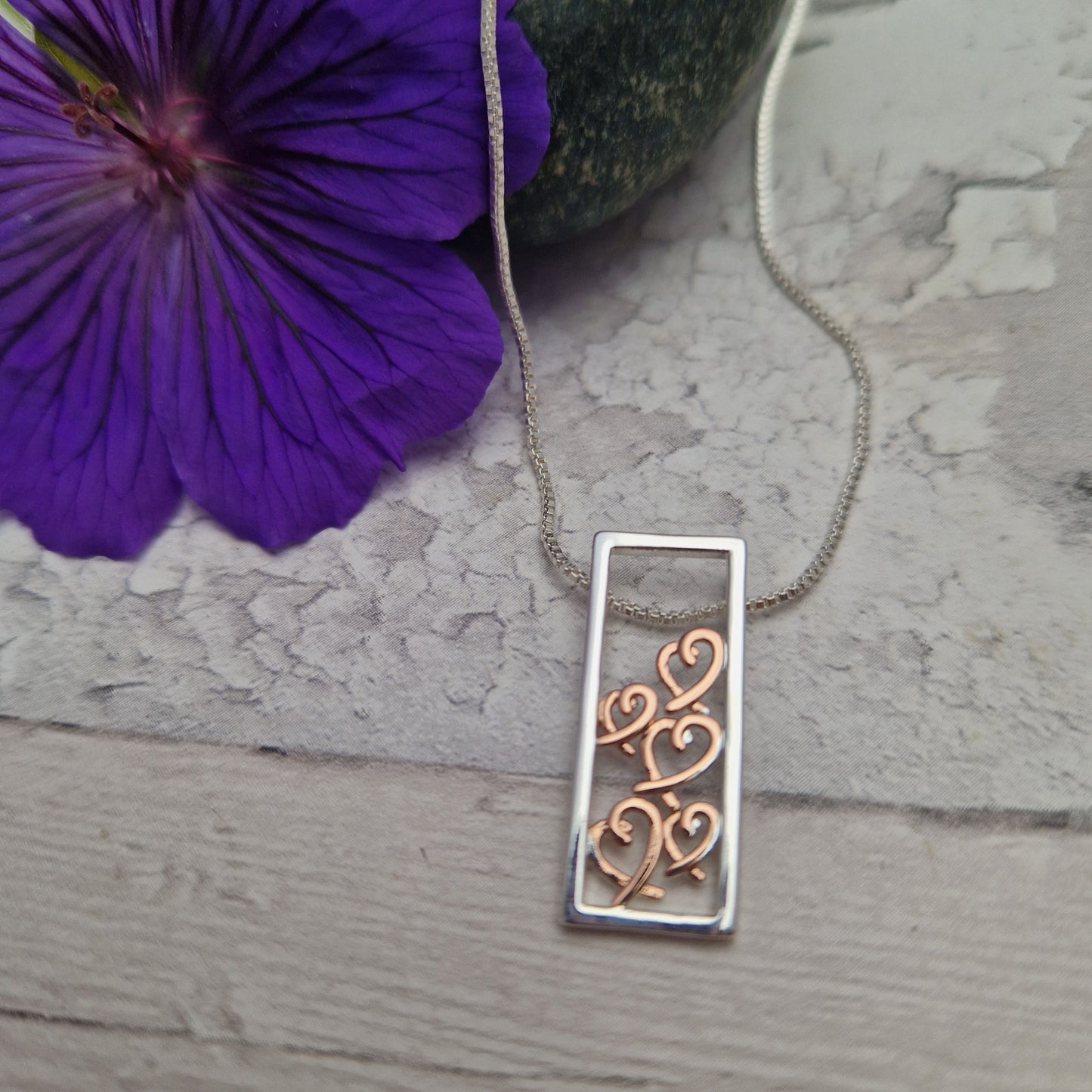 Rectabgle shaped pendant filled with rose gold love hearts.