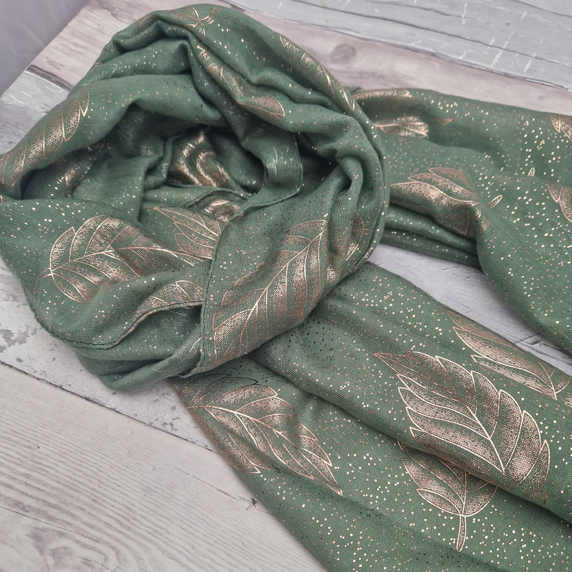 Green gift boxed scarf with a leaf print in metallic rose gold.