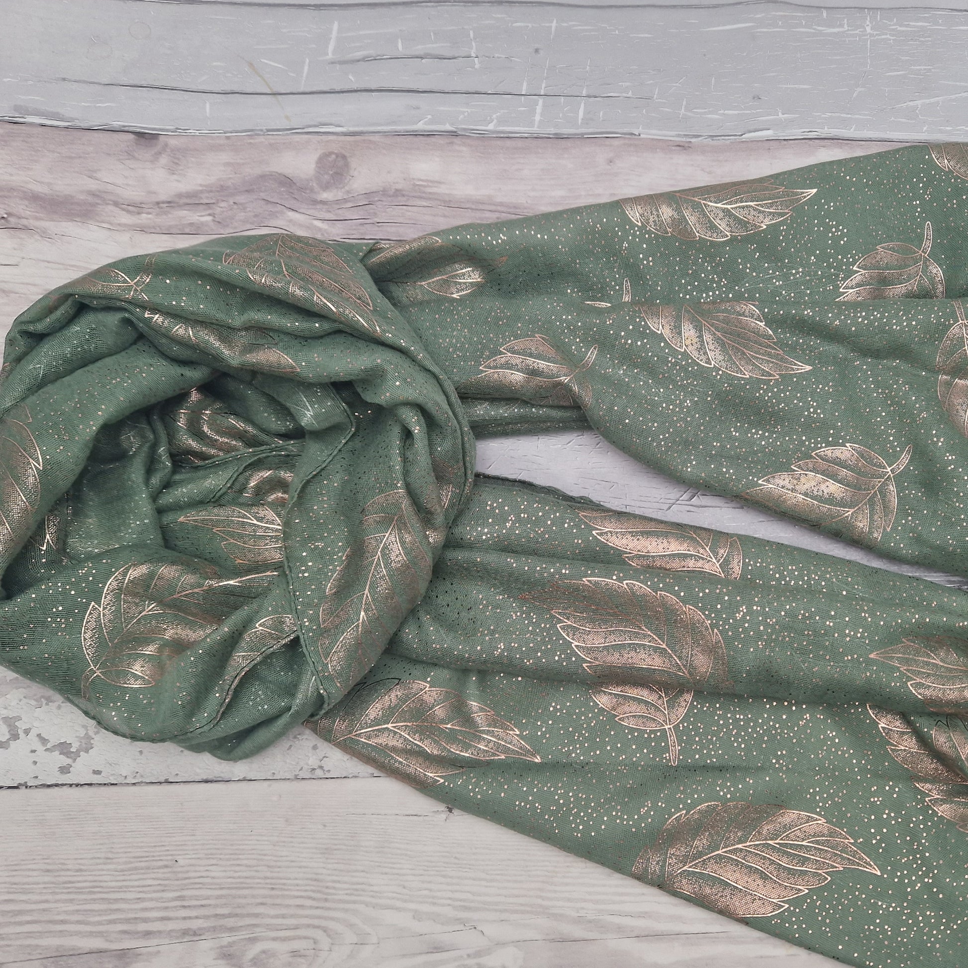 Green gift boxed scarf with a leaf print in metallic rose gold.