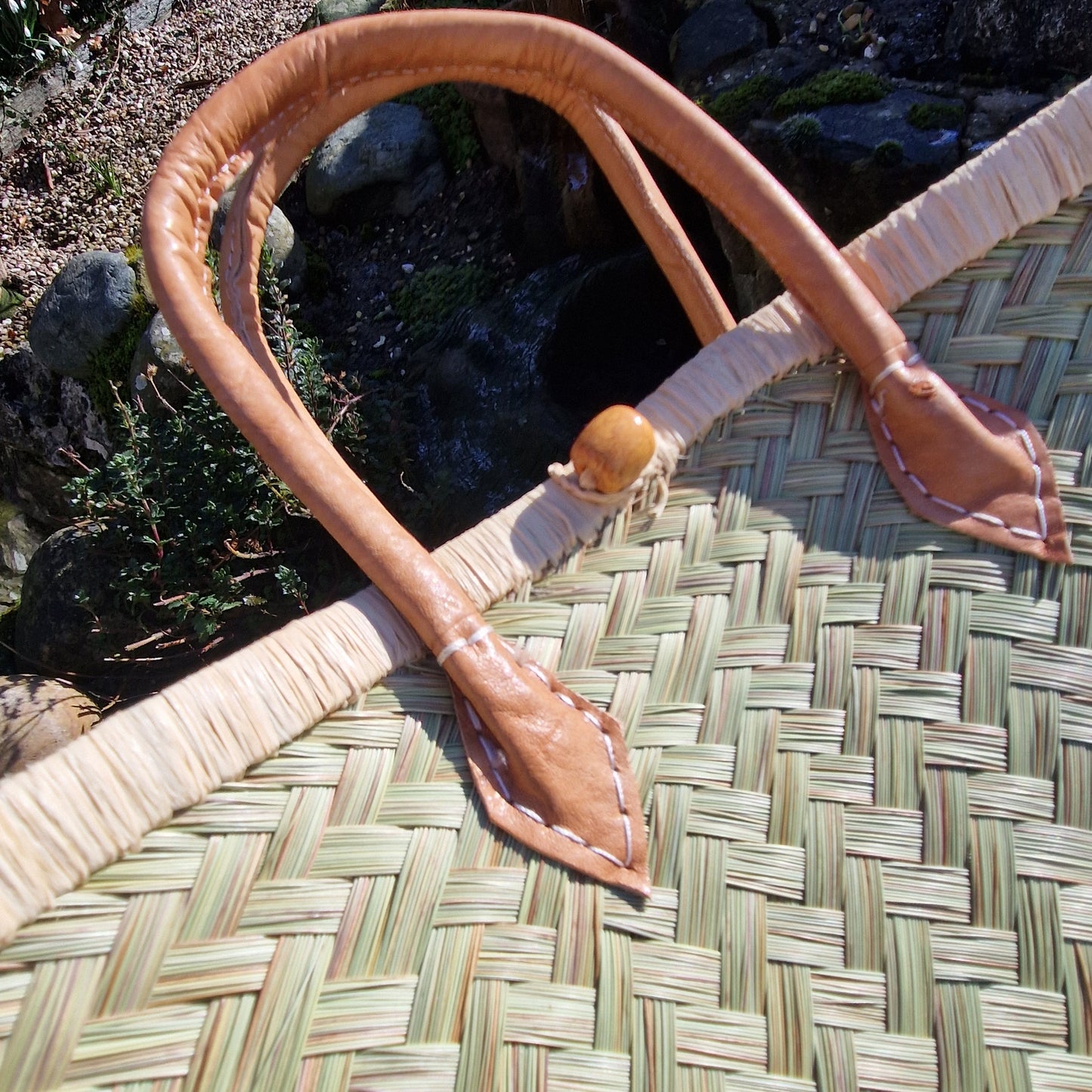 Brown leather strap with a wooden button on a woven basket.