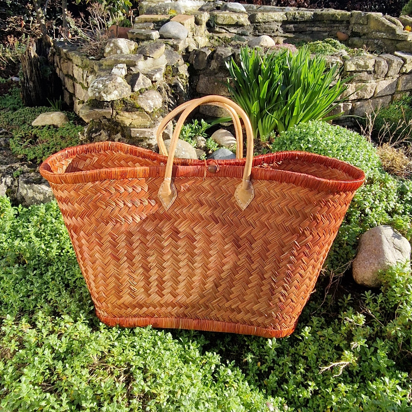 Cinnamon woven basket with leather handles and a toggle closer.