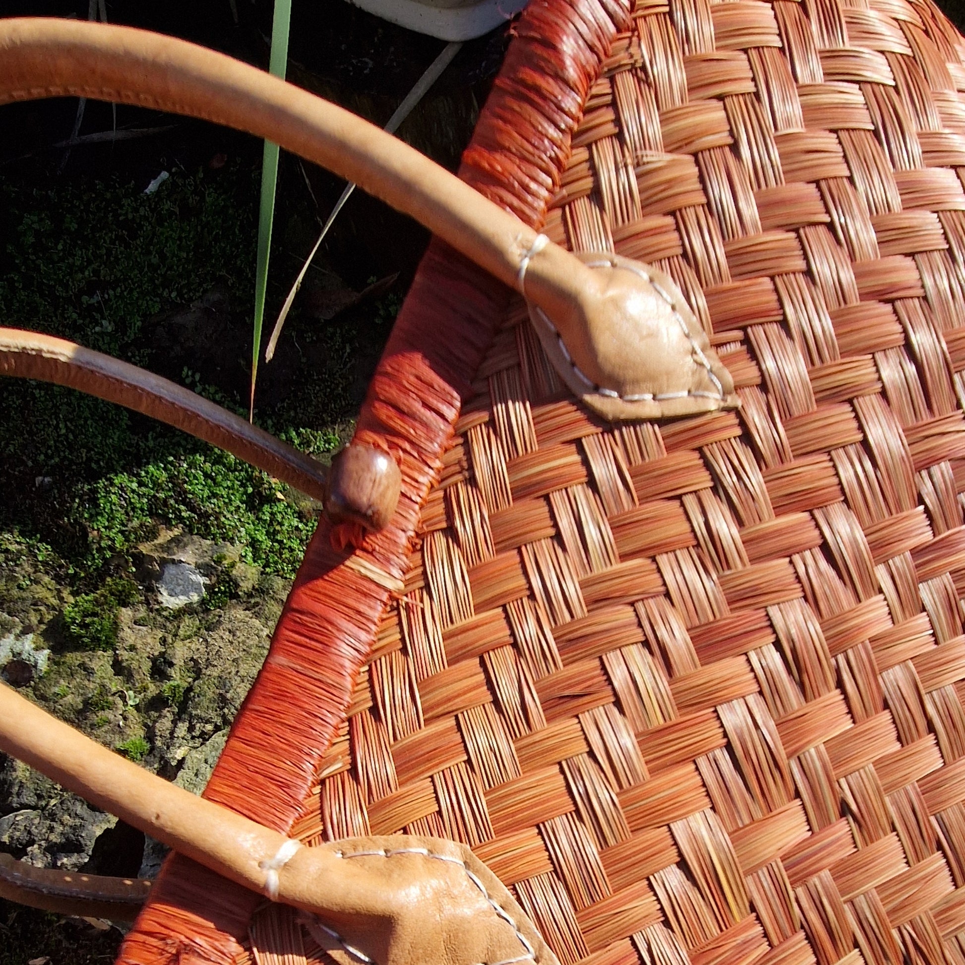 Close-up of a woven basket with a wooden handle against a natural background