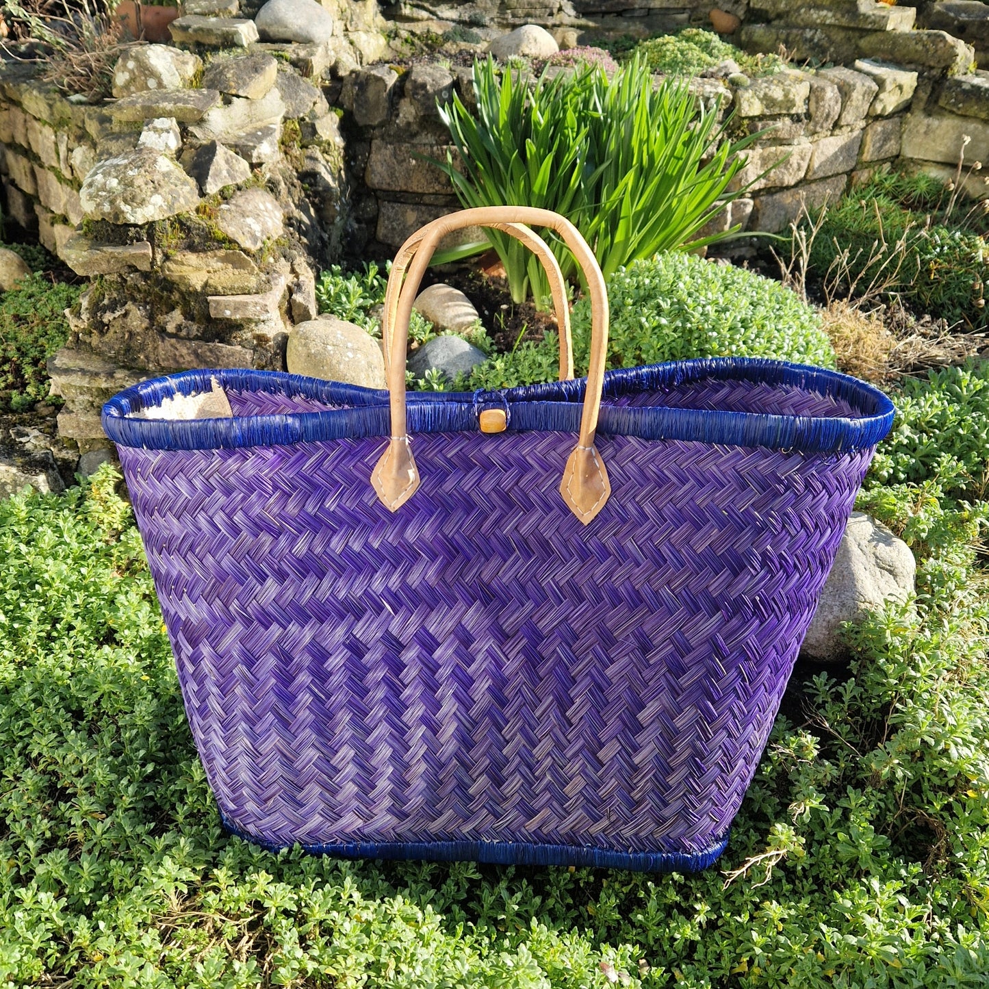 Blue woven basket with leather handles and a toggle closer.