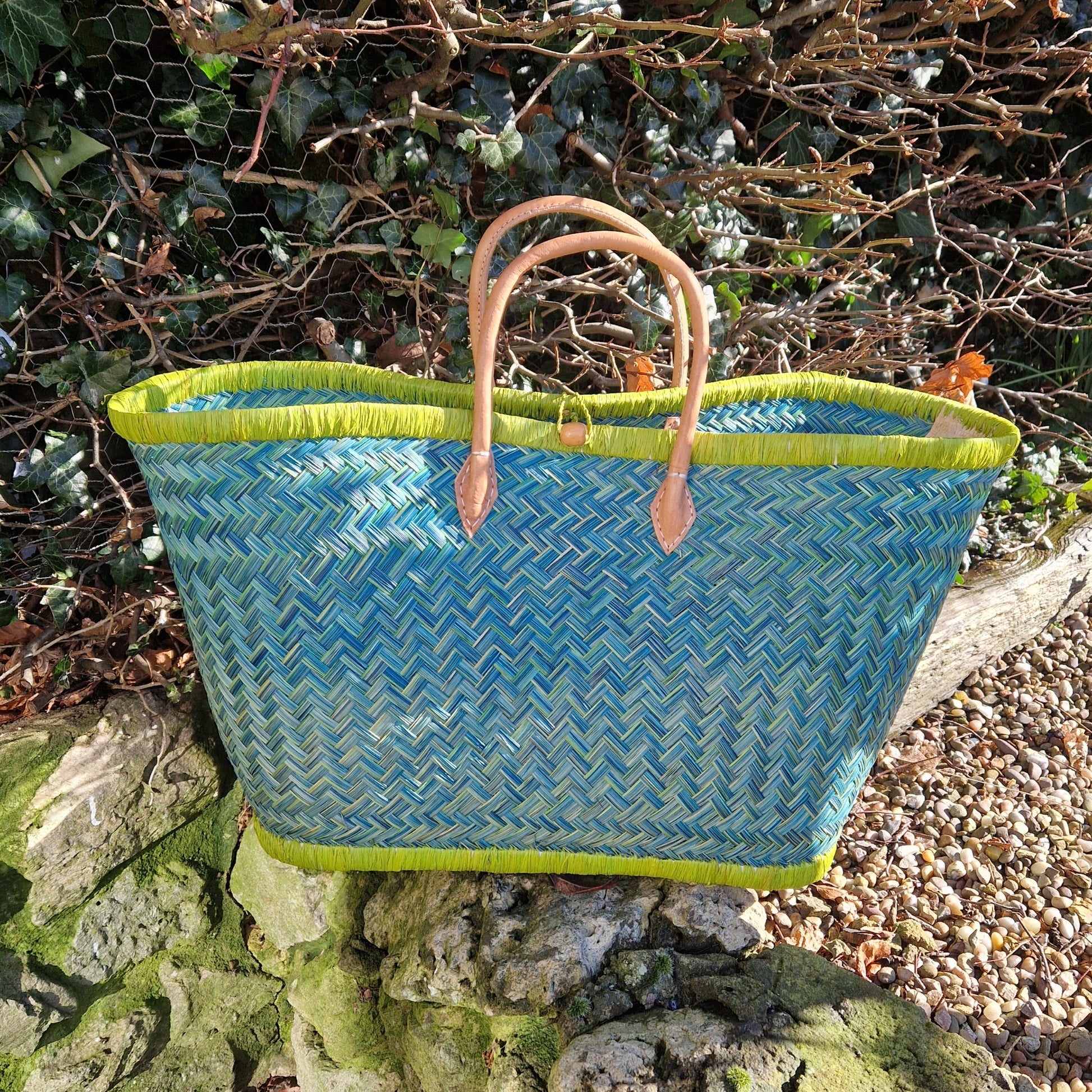 Woven basket with lime green and blue pattern and a leather handle.