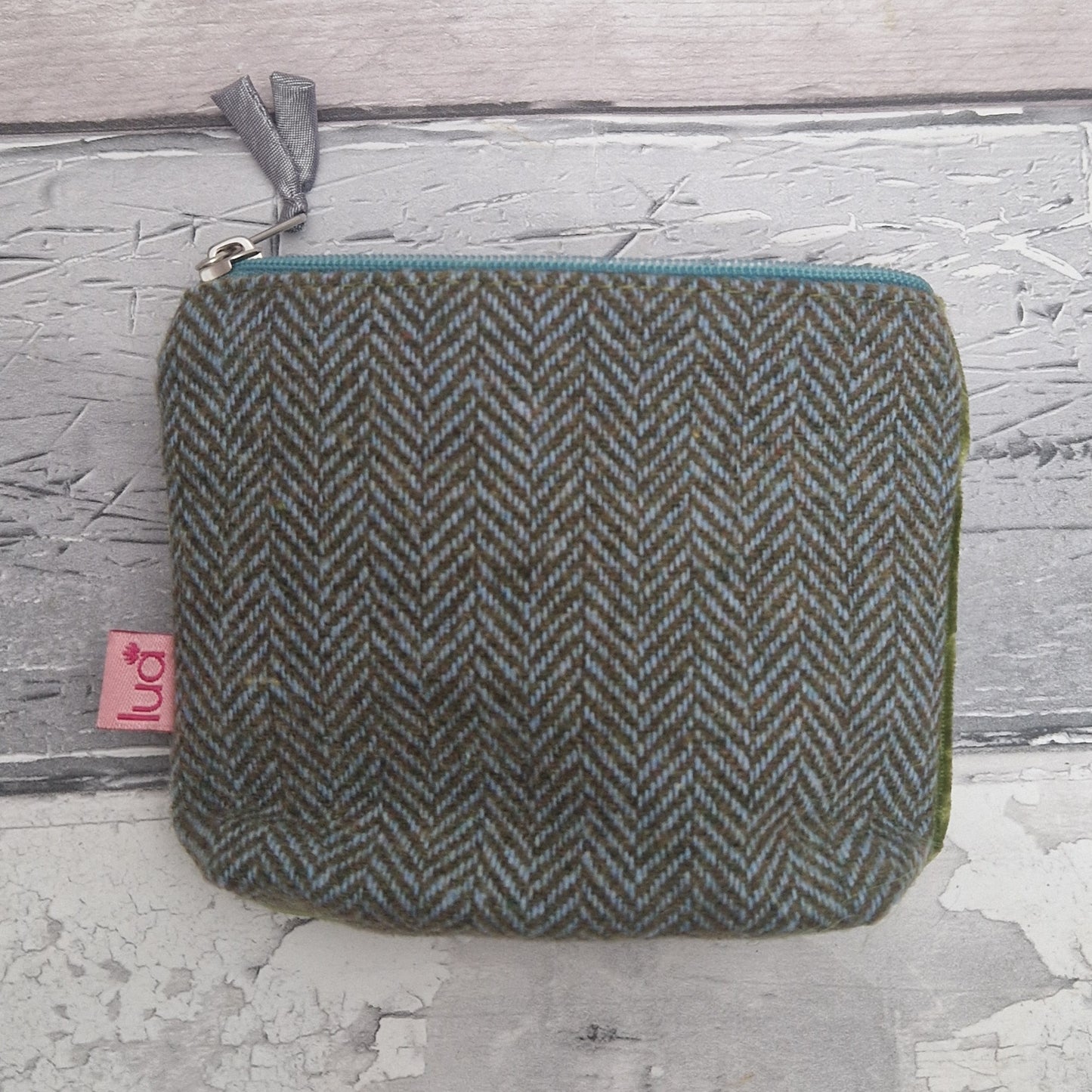Herringbone patterned pouch with a visible brand tag on a textured surface