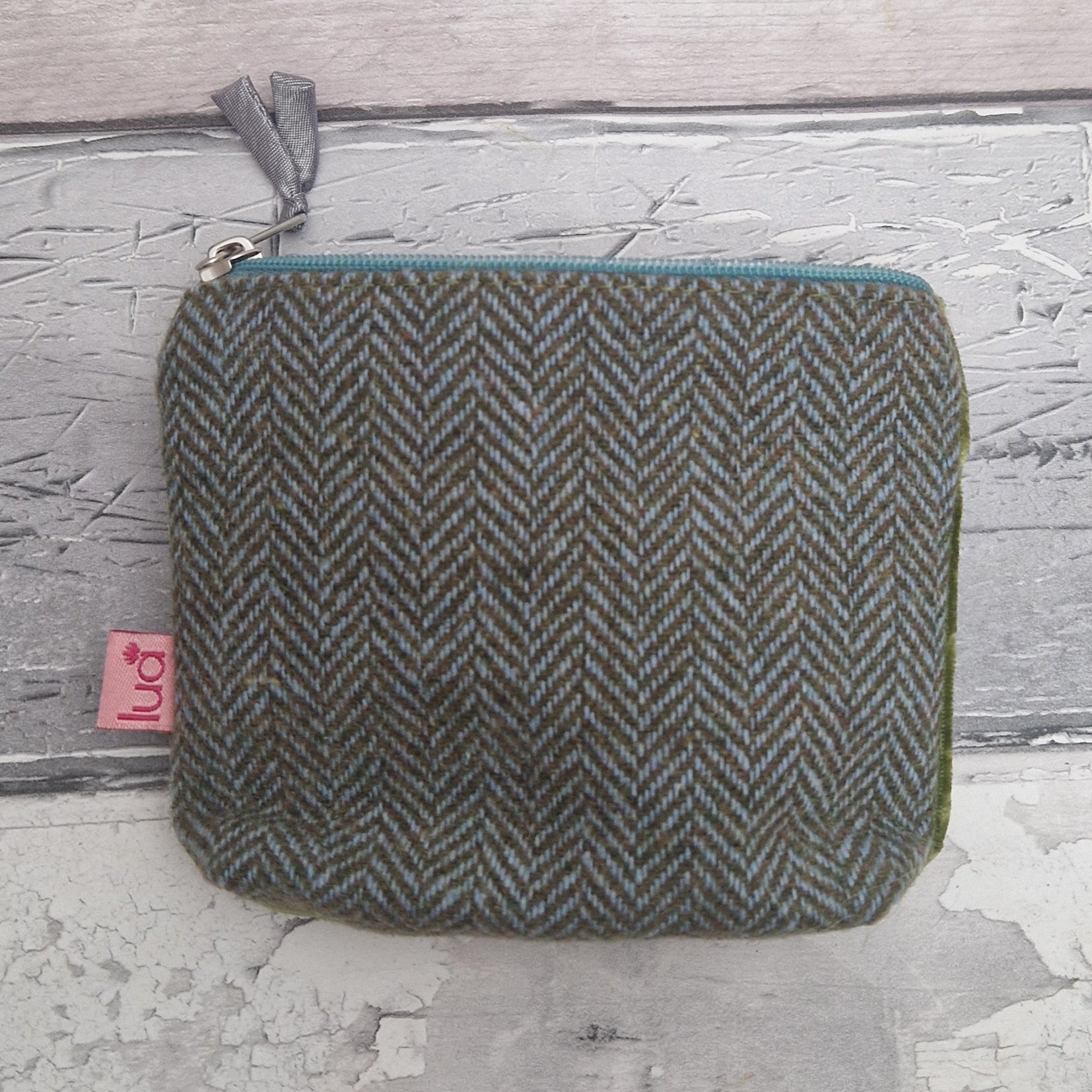 Herringbone patterned pouch with a visible brand tag on a textured surface