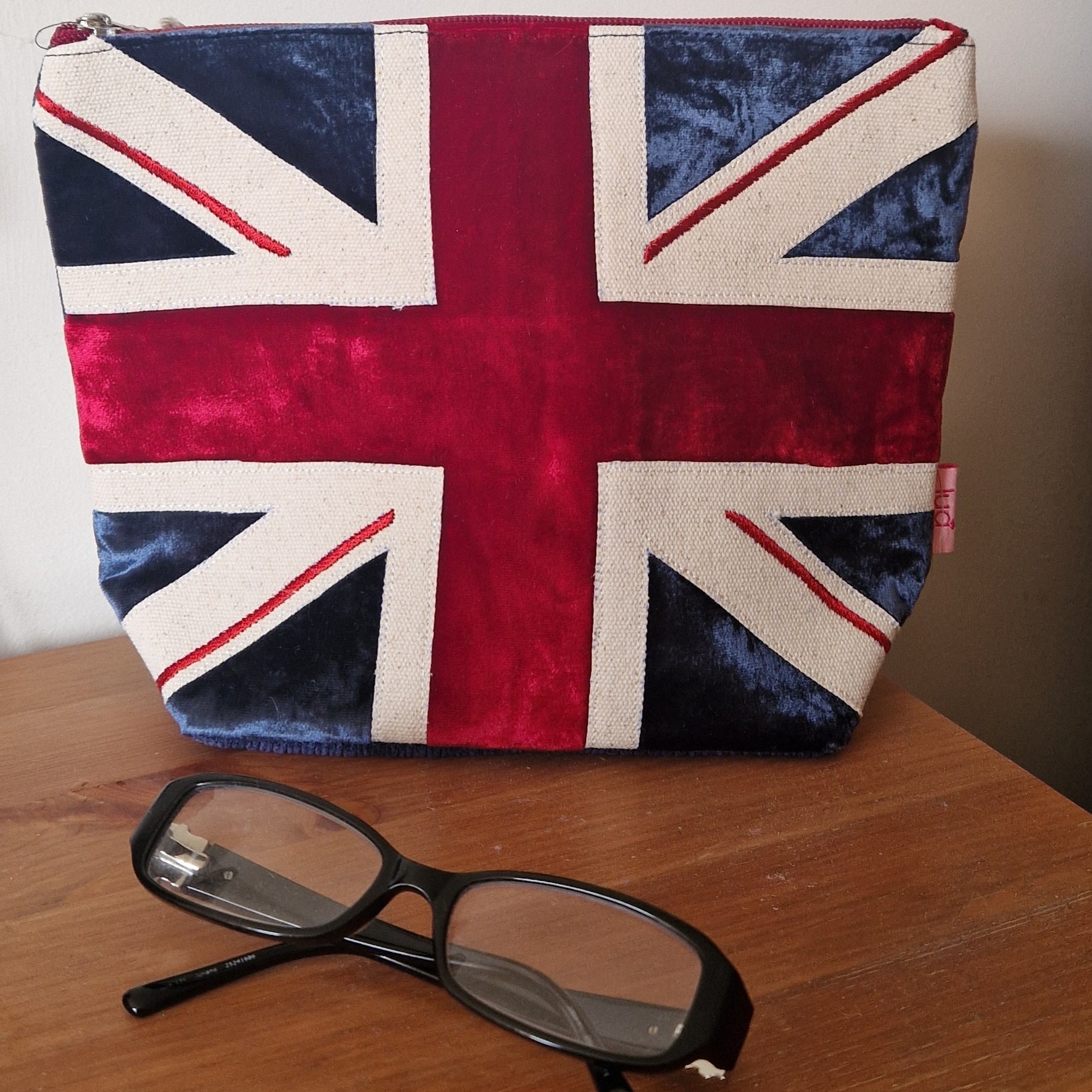 Pouch with Union Jack design on a wooden surface with glasses in front