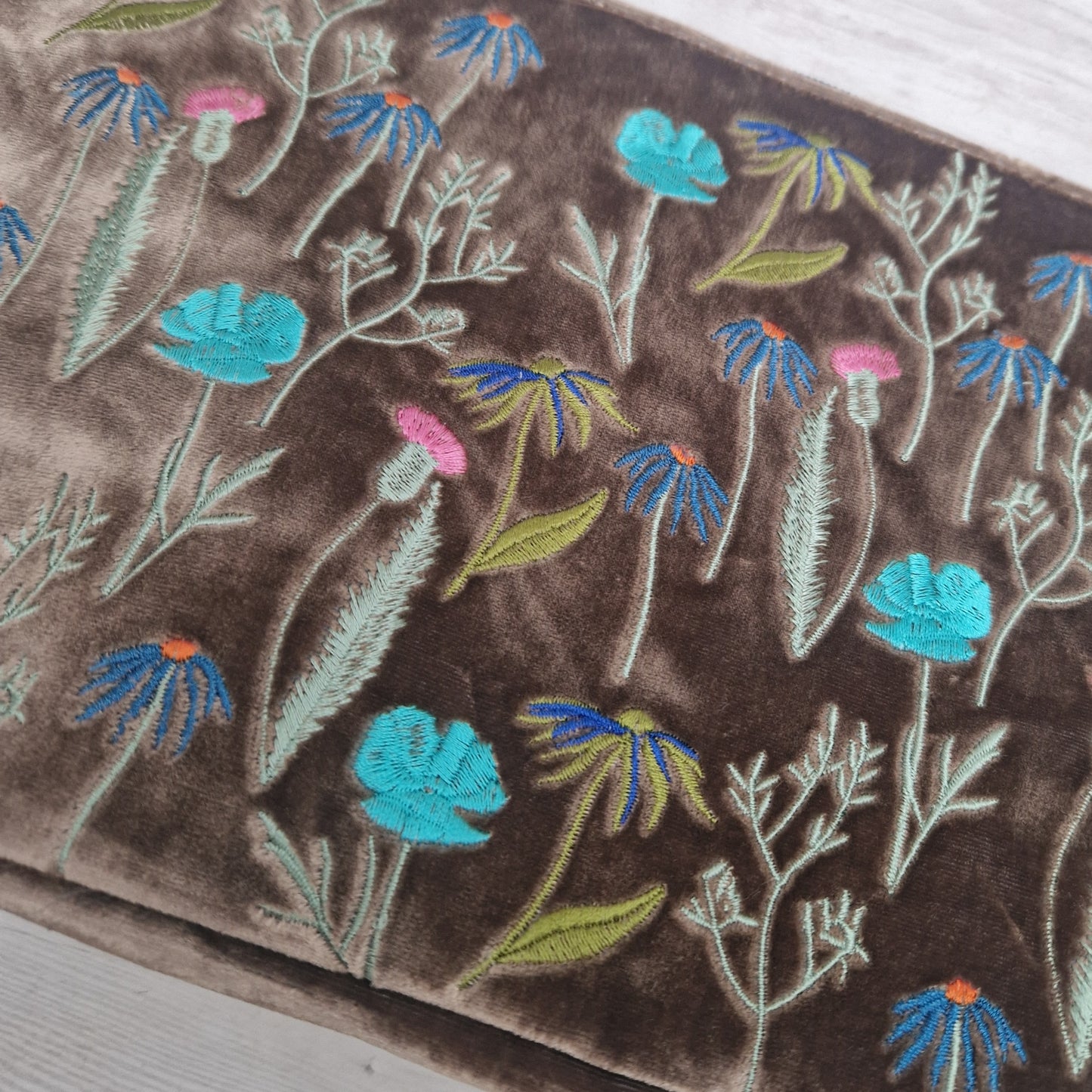 Embroidered floral pattern on a brown fabric background