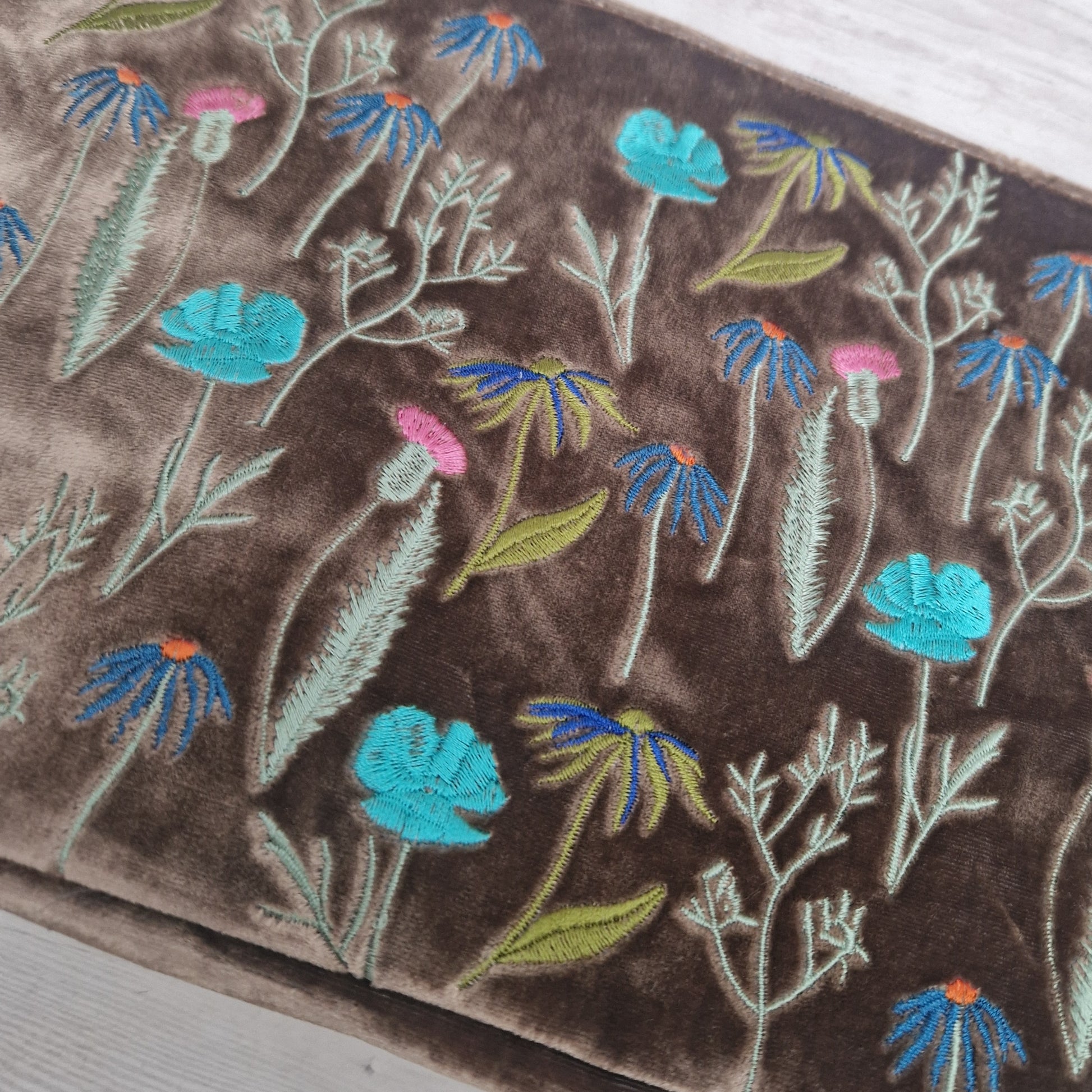 Embroidered floral pattern on a brown fabric background