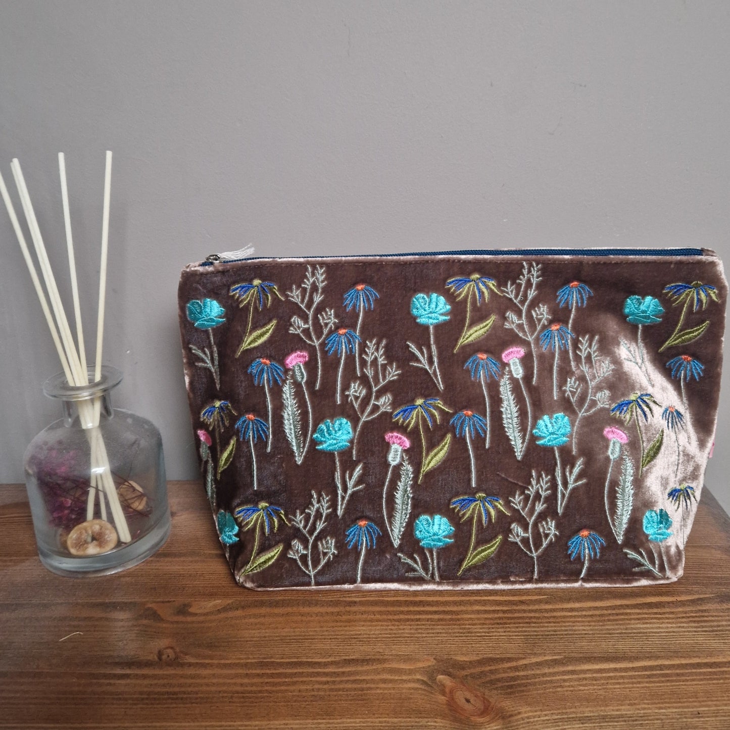 Floral-patterned pouch on a wooden surface with a gray background