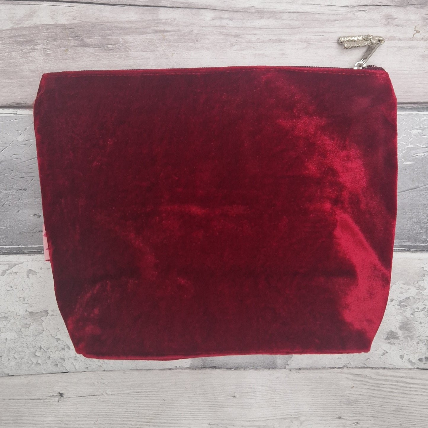 Red velvet pouch with a zipper on a wooden surface