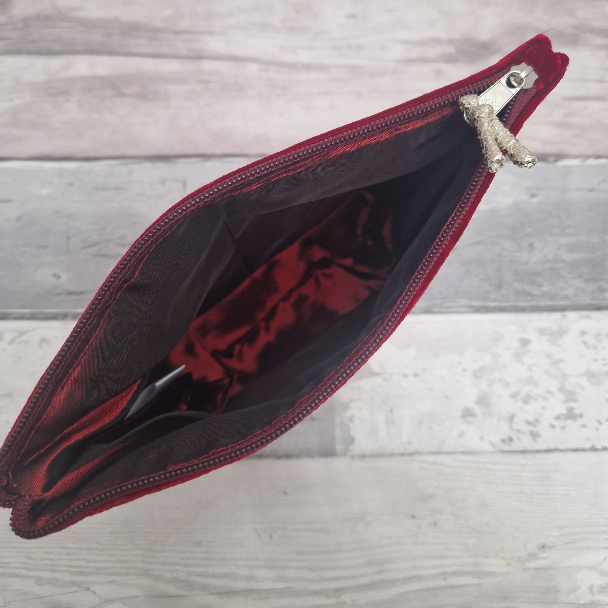 Open red pouch with a zipper on a wooden surface