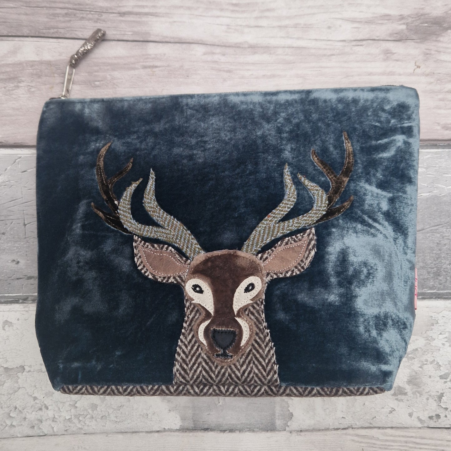 Blue velvet pouch with a Highland Stag design on a wooden surface