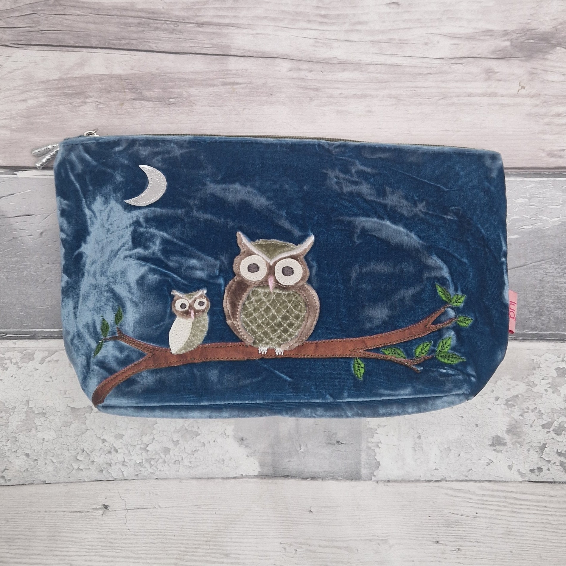 Blue pouch with owl design on a wooden surface