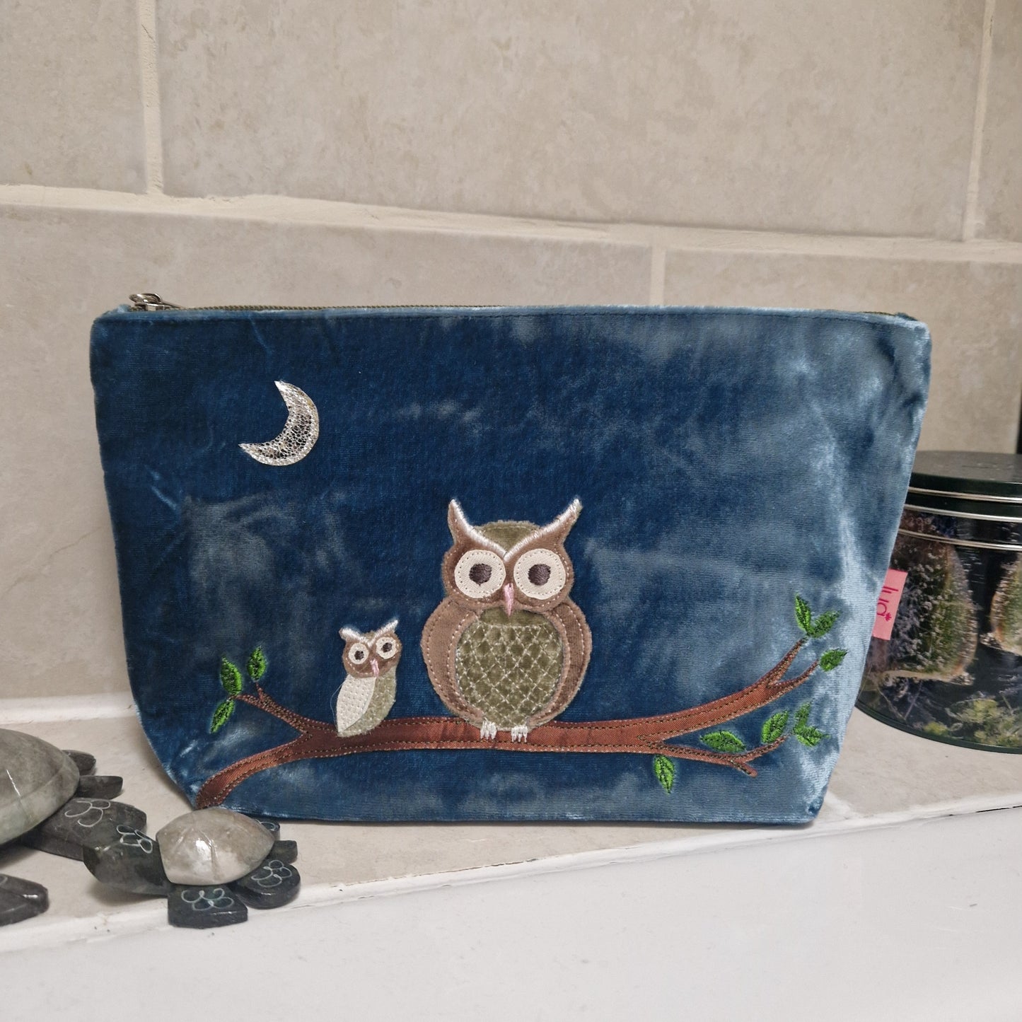 Blue pouch with owl design on a tiled wall background