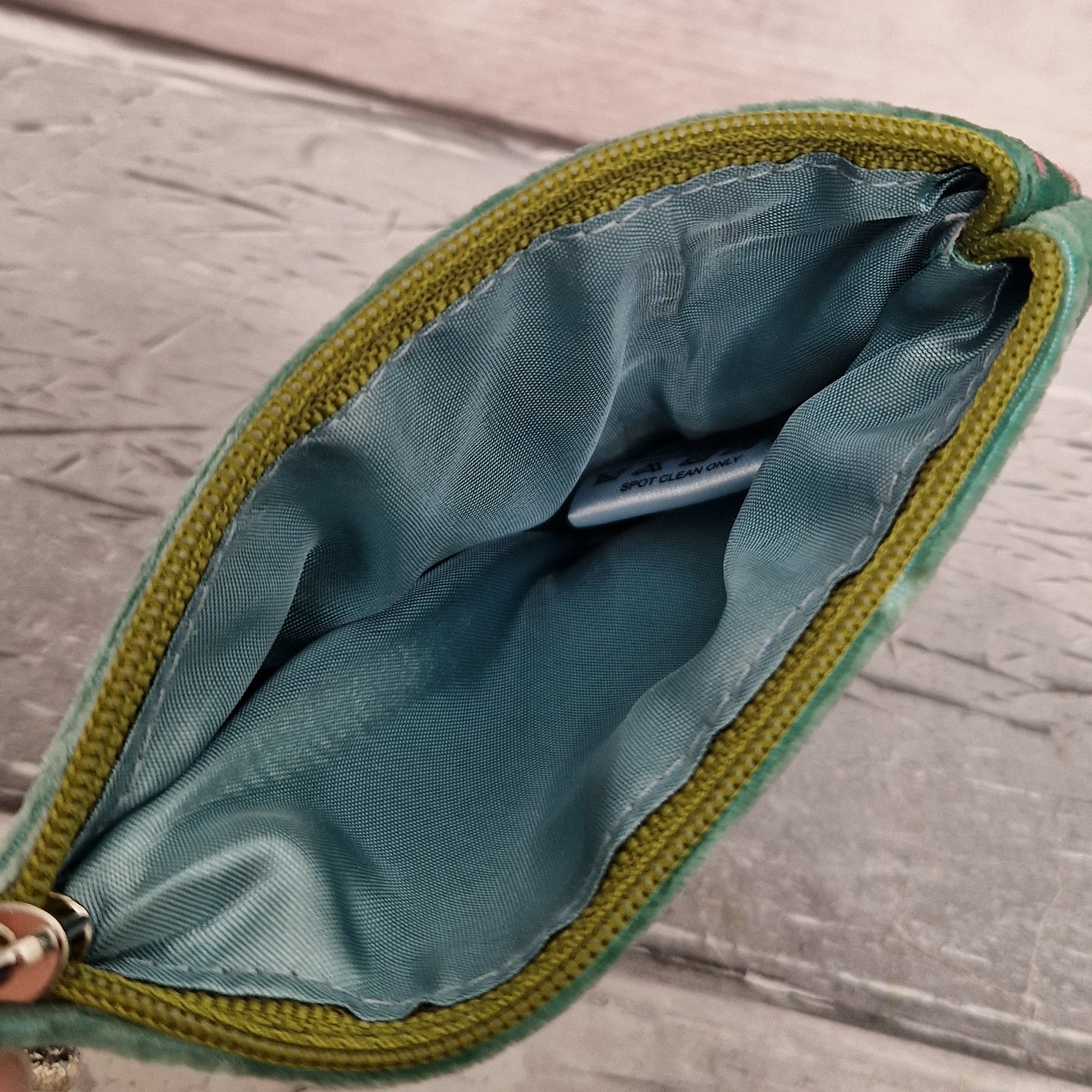 Inside view of a silk lined coin purse with a green zipper.
