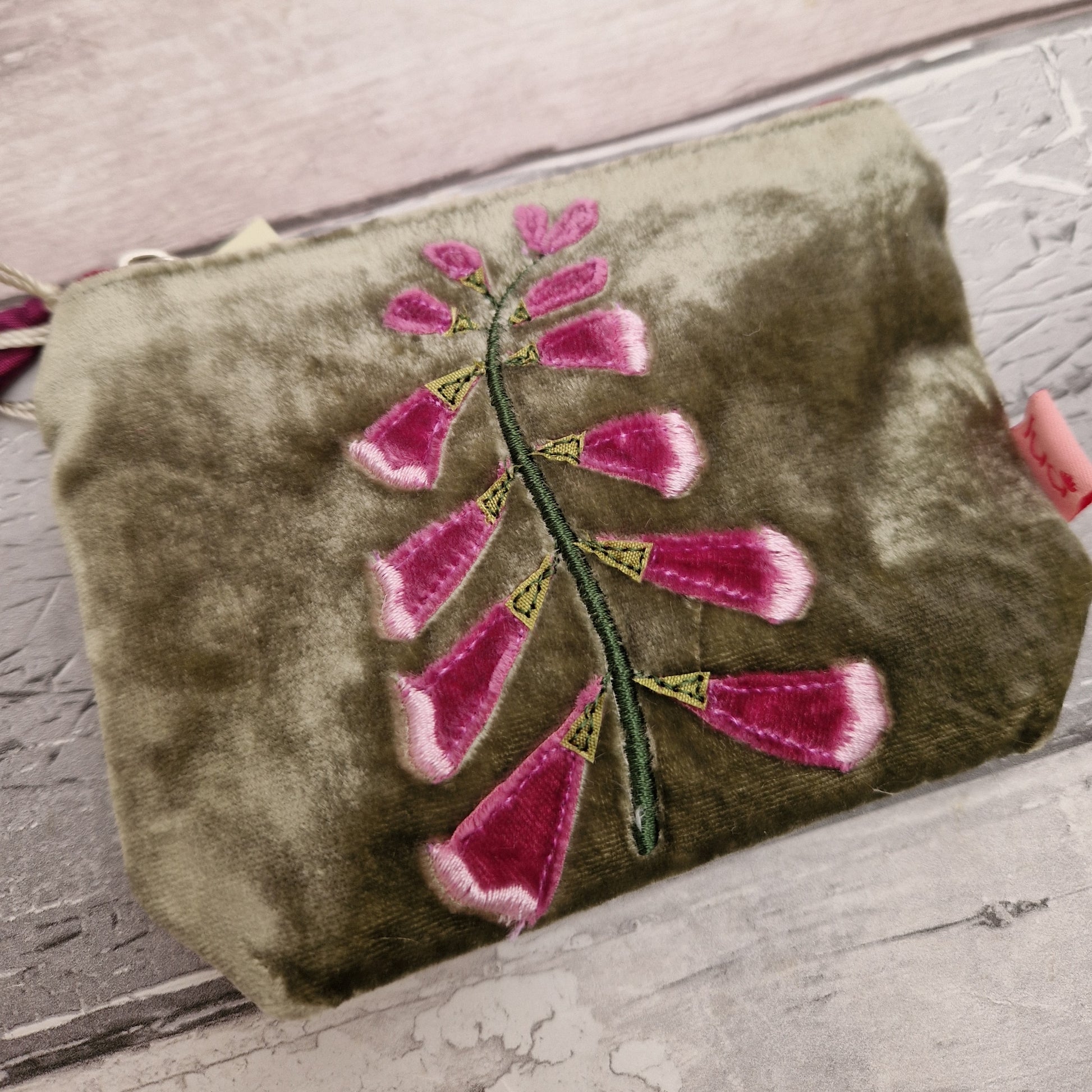 Green velvet coin purse decorated with a pink foxglove stem.