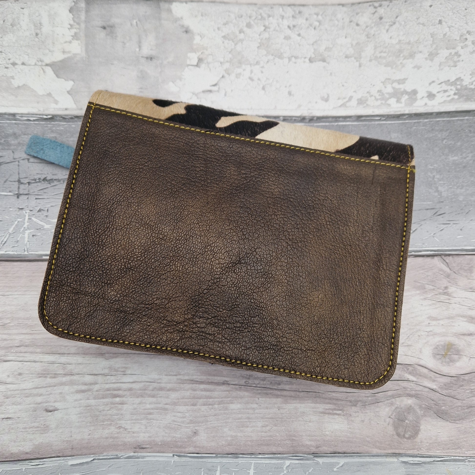 Brown leather satchel style bag with textured front panel in cow hide print.