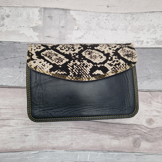 Black leather bag with envelope style and textured panel of snakeskin print.