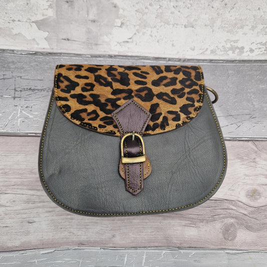 Leather saddlebag shaped bag with a grey front and a textured panel of jaguar print.