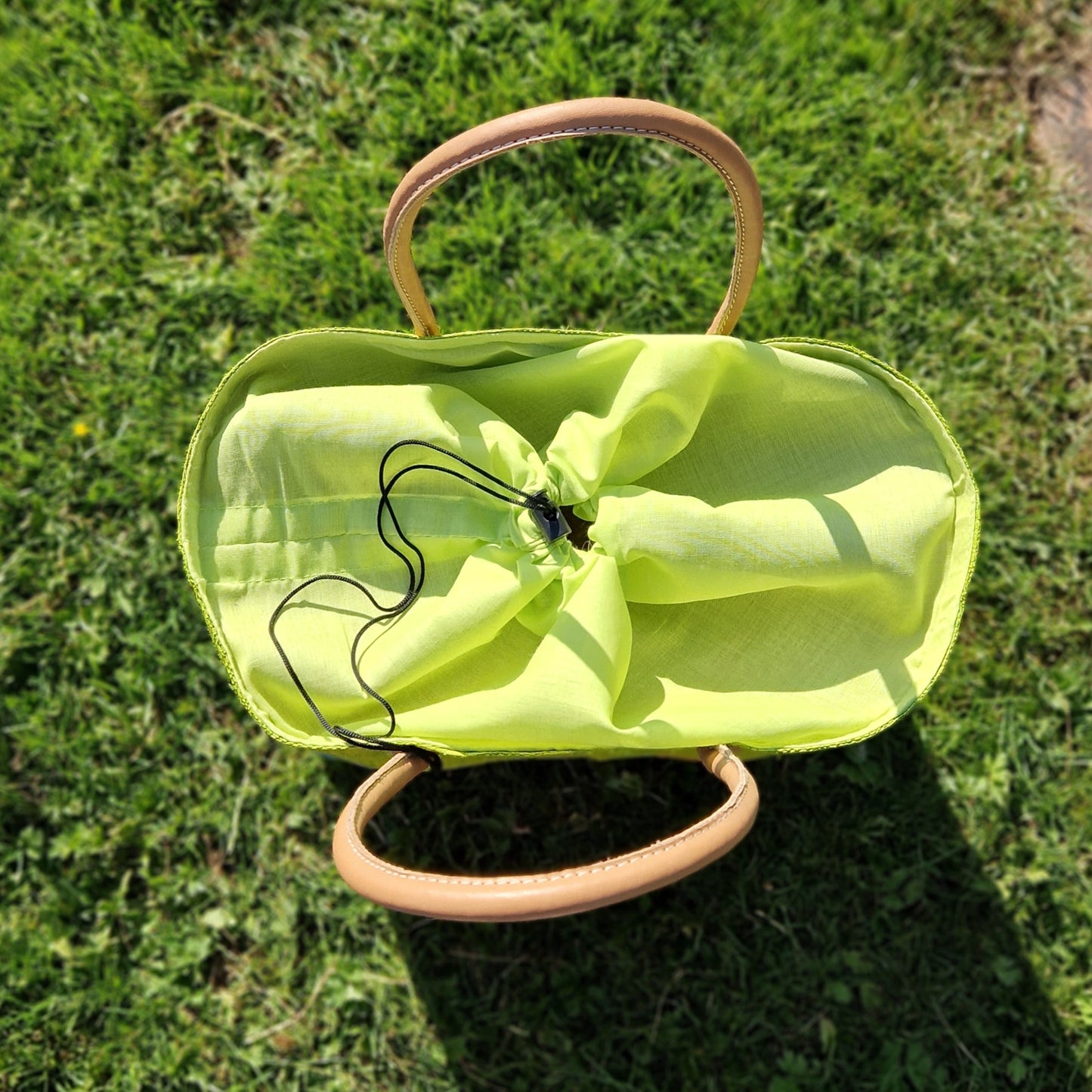 Lime green raffia basket showing the drawstring top closed.
