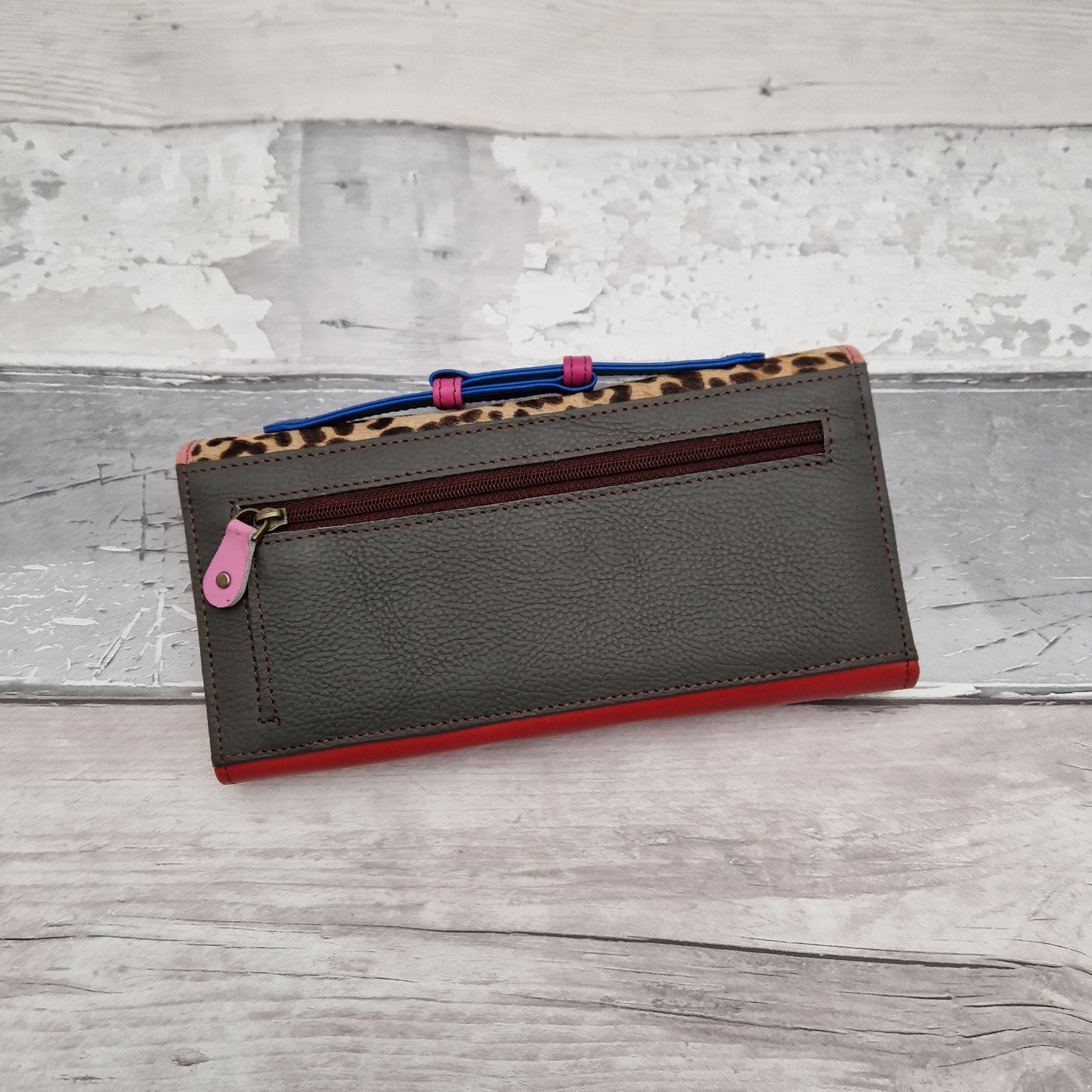 Red leather purse with a leopard print textured panel.