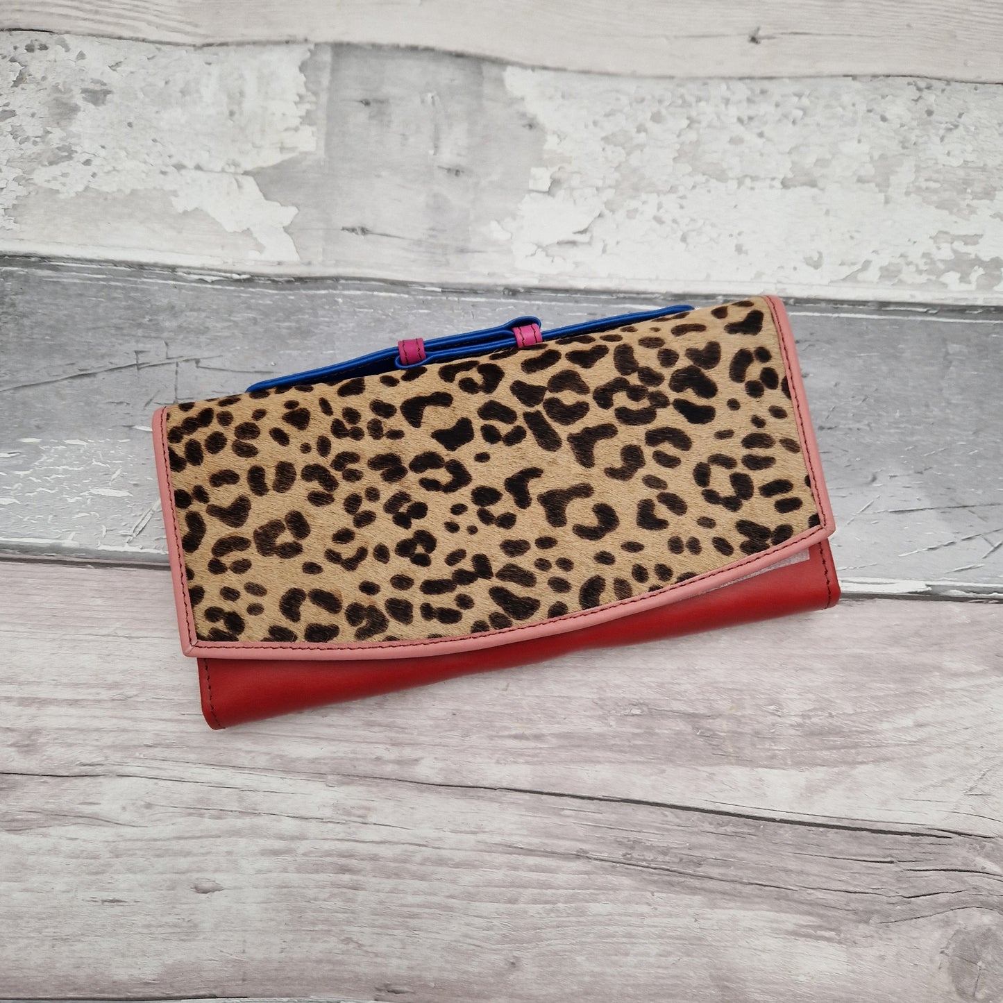 Red leather purse with a leopard print textured panel.