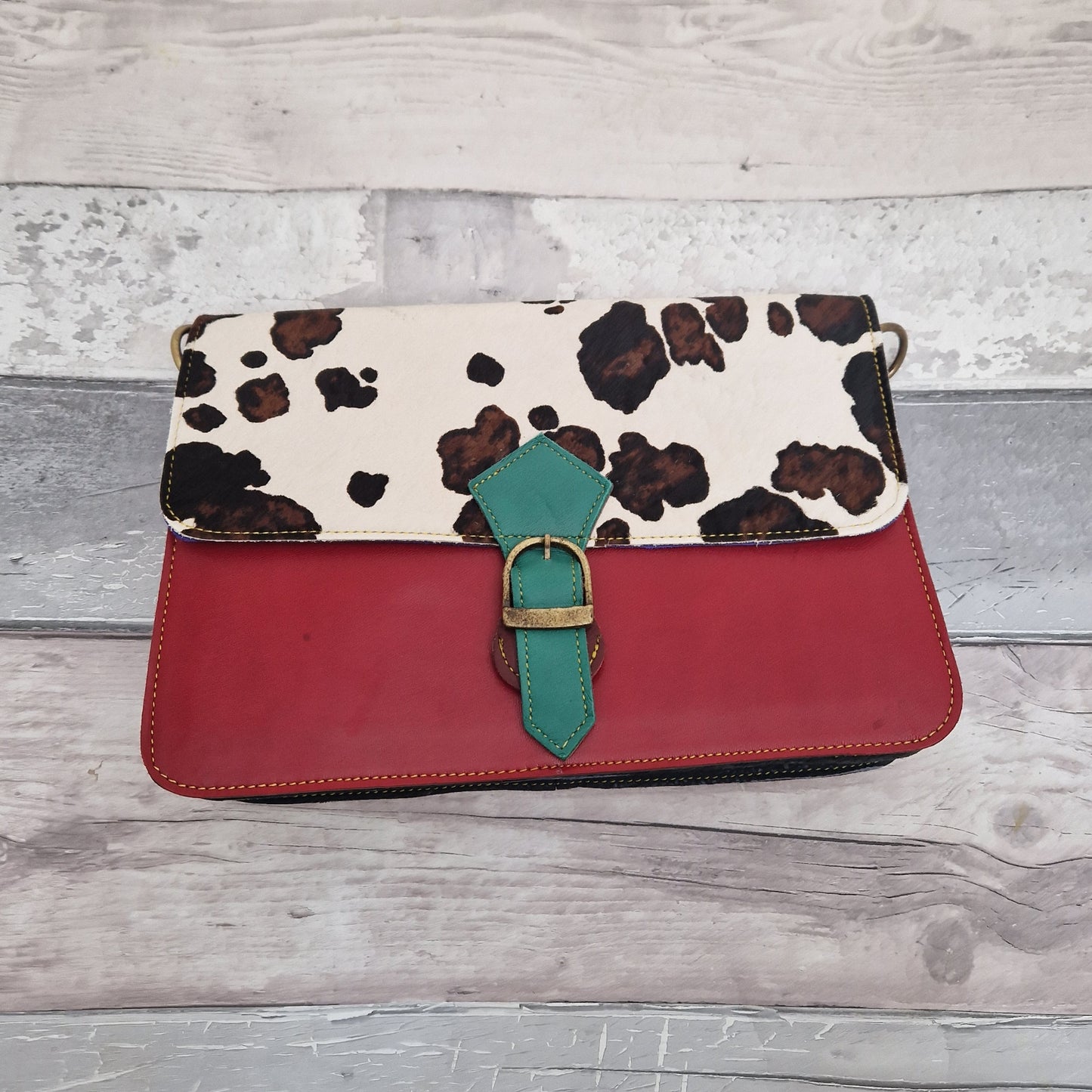 Striking red leather bag with a textured panel of black and white cow print.