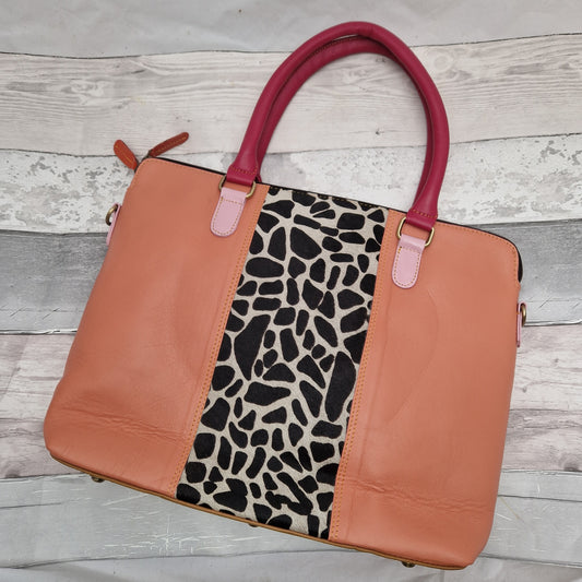 Peach coloured leather bag with pink handles. Decorated with a panel of textured giraffe print.