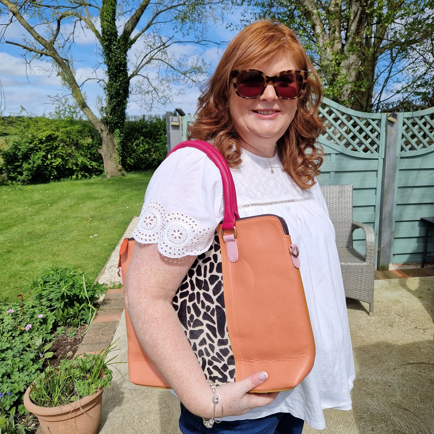 Lady holding a peach leather bag with a giraffe print panel.