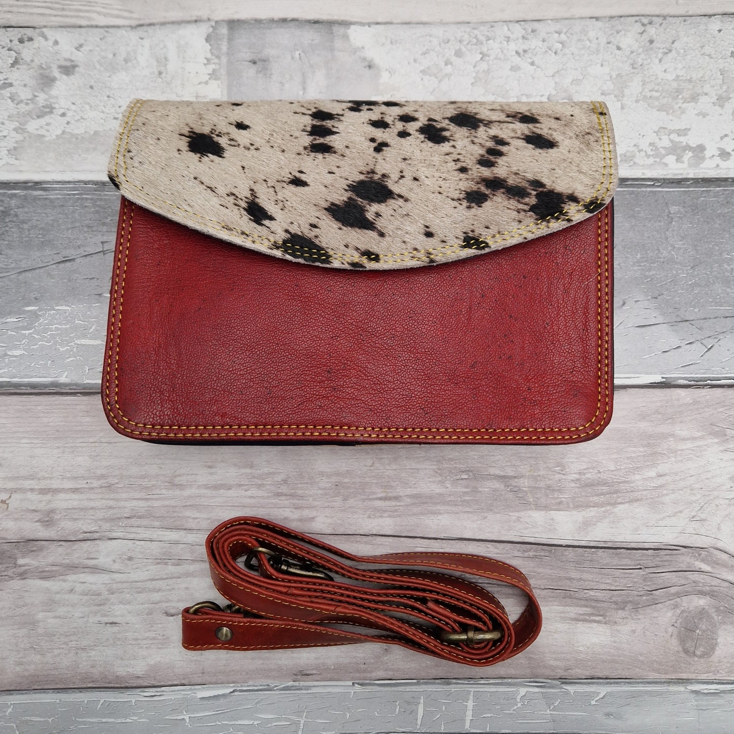 Speckled red leather bag with a cow print envelope panel.