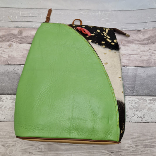 Emerald green leather back pack with a textured panel of black and white cow print. 