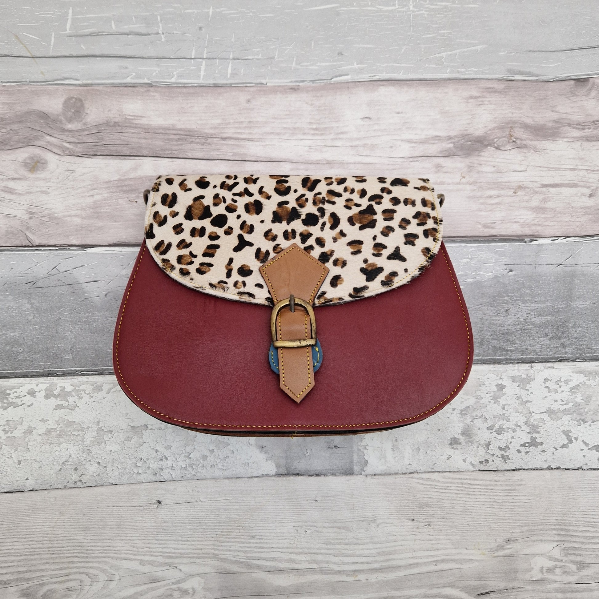 Maroon leather bag with a textured panel of leopard print.
