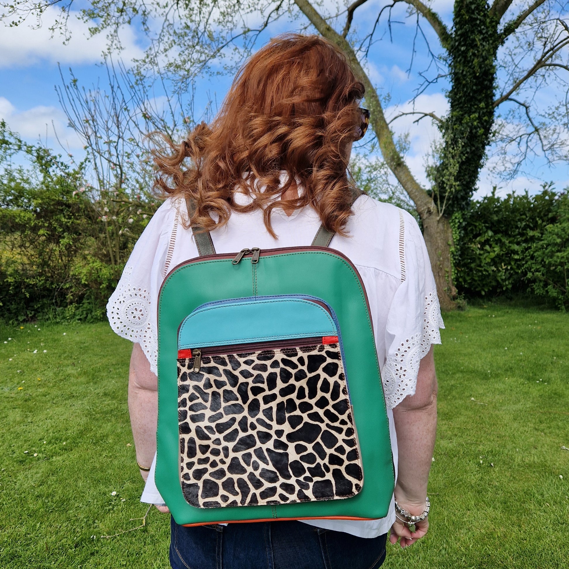 Lady wearing a green leather back pack with a giraffe print panel.