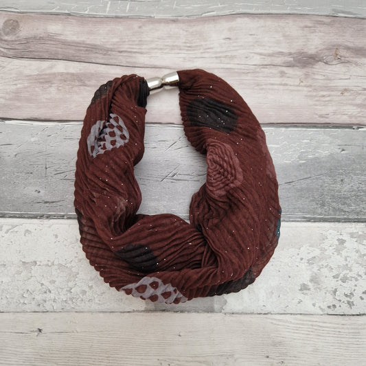 Rust coloured magnetic neck scarf decorated with patterened spots in black, white and peach tones.