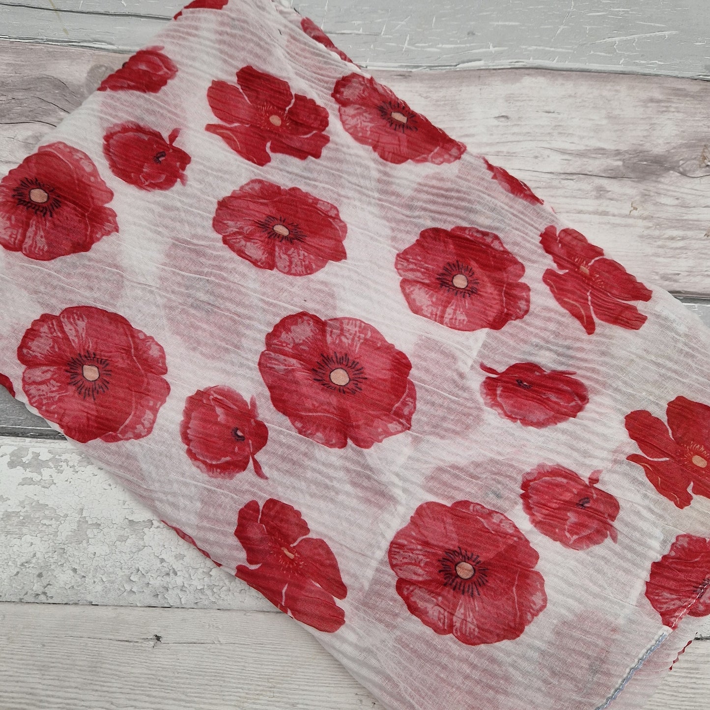White scarf in a crinkle fabric decorated with red poppies.