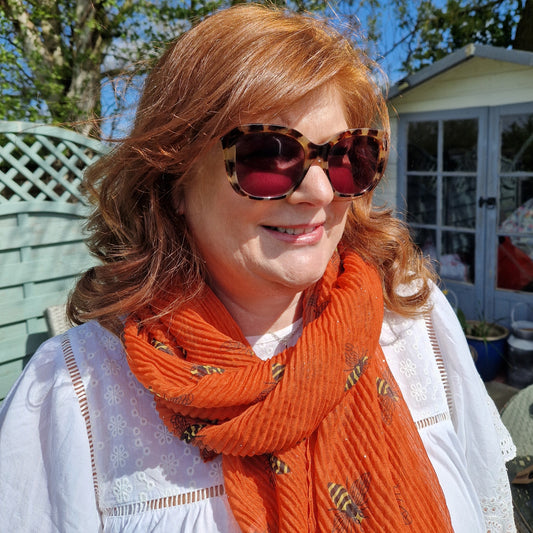 Lady wearing orange scarf with bee pattern.
