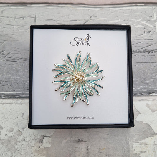 Decorative brooch on a branded card with a textured gray background