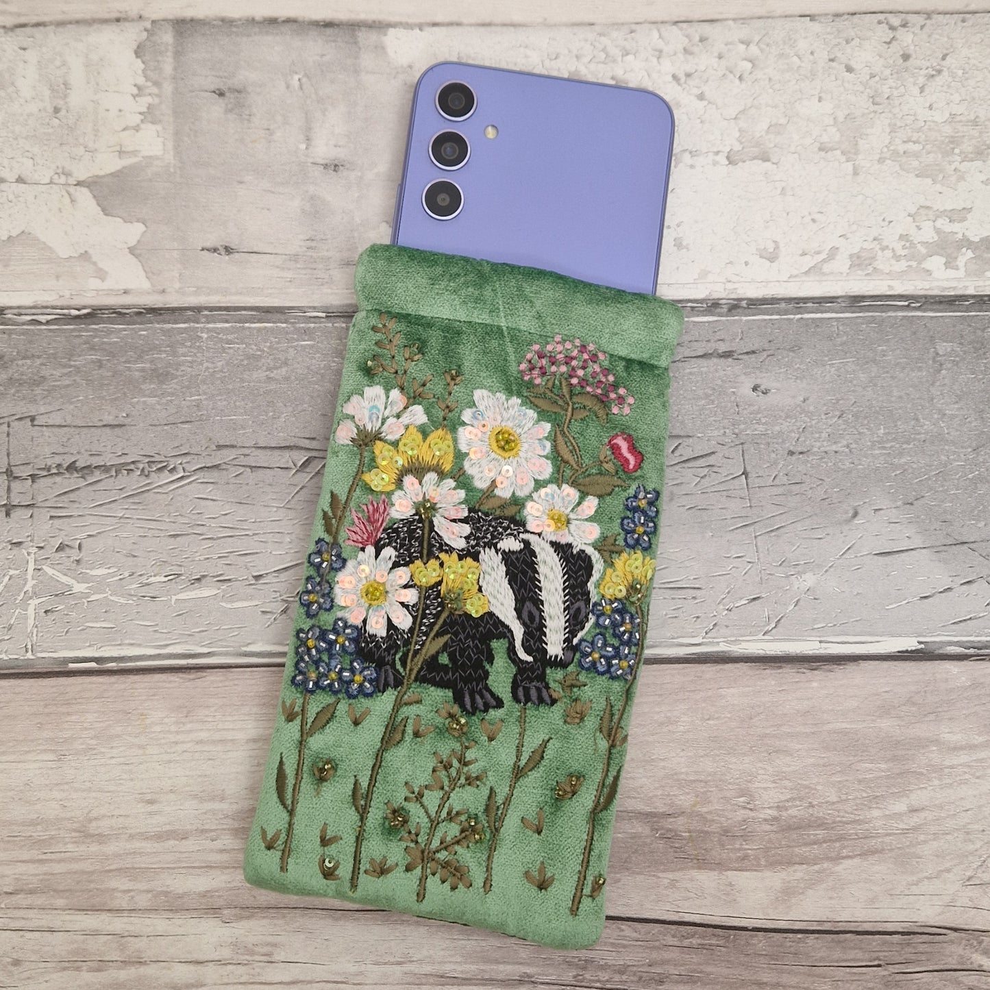 Green velvet glasses case decorated with an embroidered scene featuring a Badger in a flower garden. The scene is finished with beads and sequins.