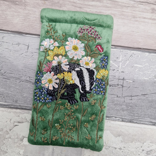 Green velvet glasses case decorated with an embroidered scene featuring a Badger in a flower garden. The scene is finished with beads and sequins.
