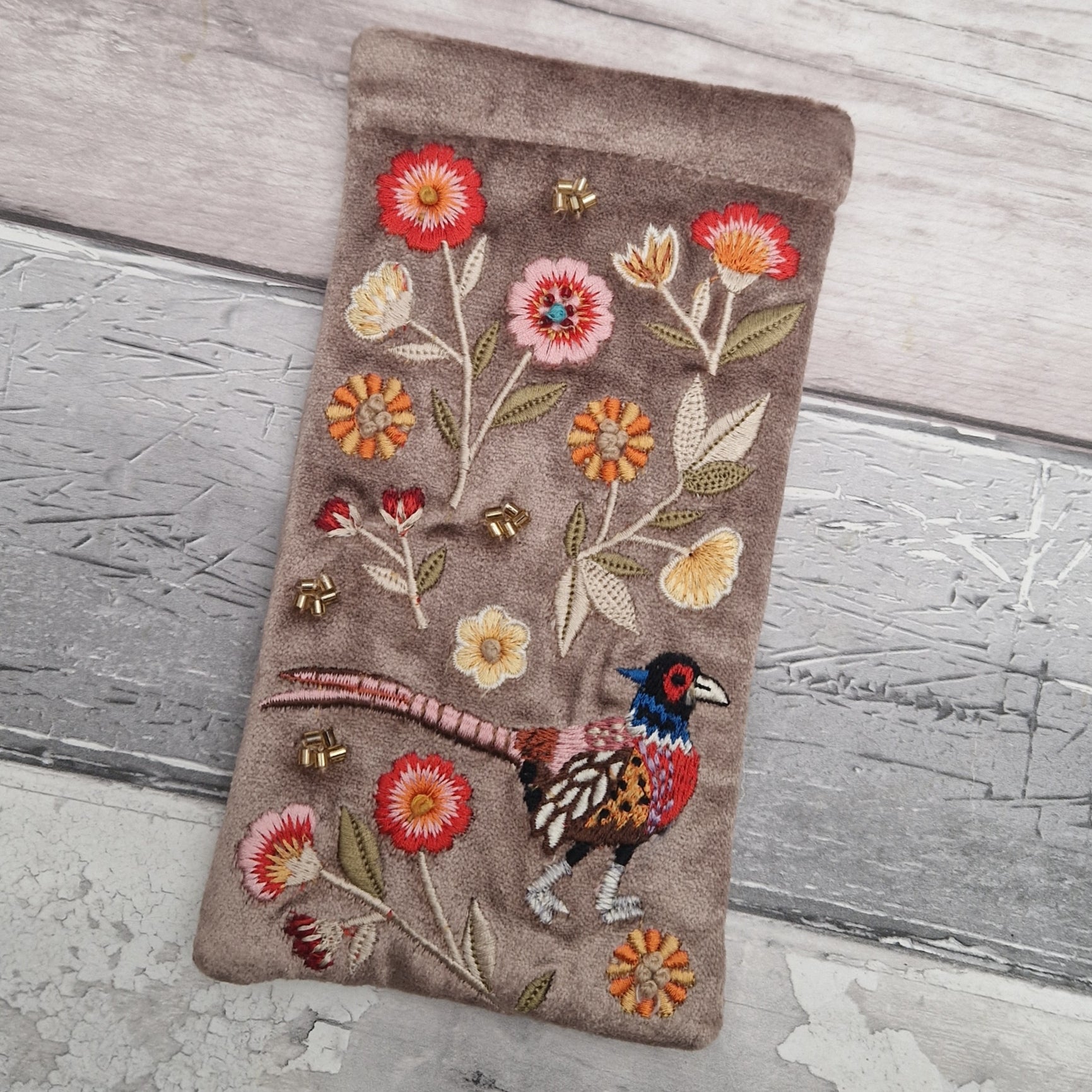 Fawn coloured velvet glasses case decorated with an embroidered scene featuring a Pheasant in a flower garden. The scene is finished with beads and sequins.
