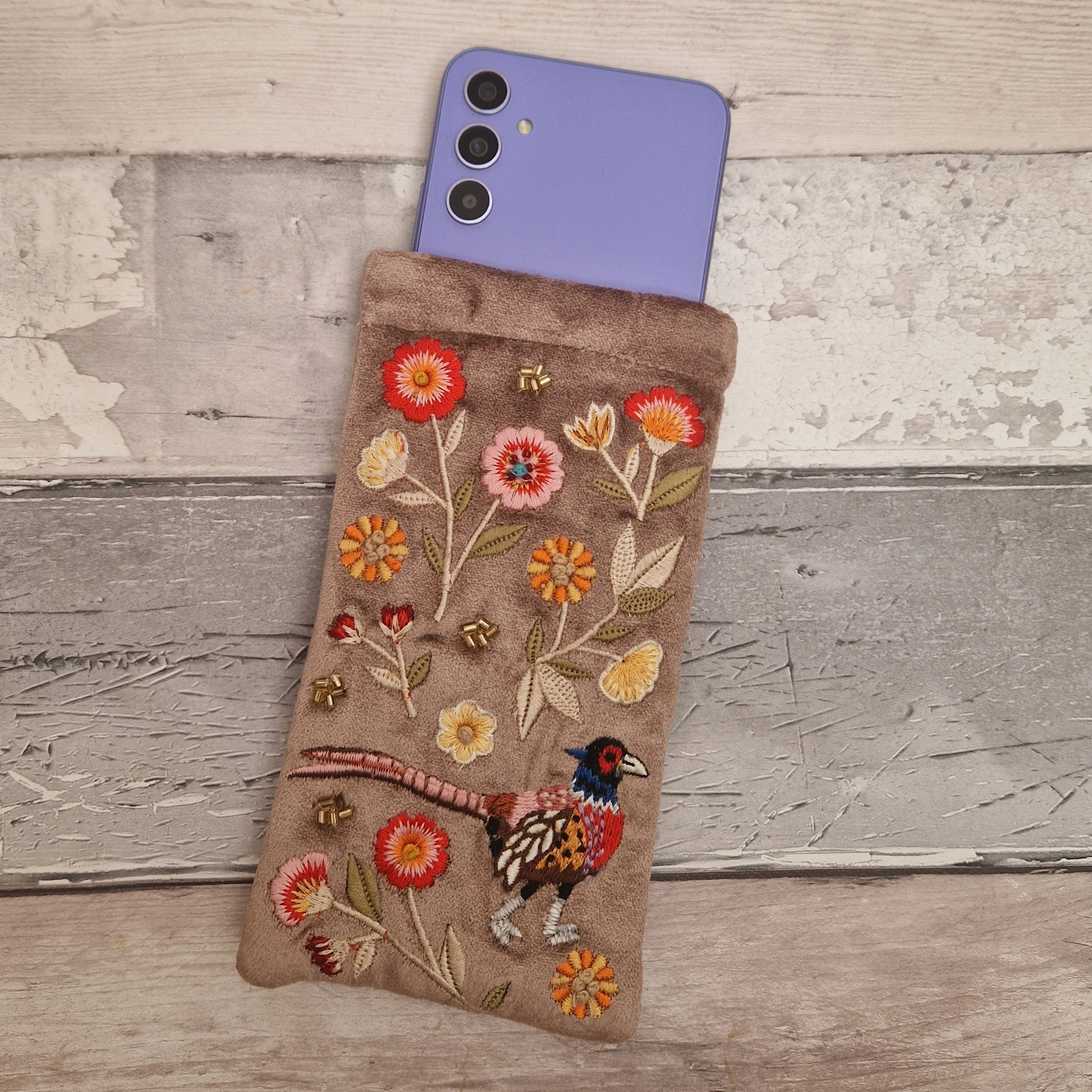 Fawn coloured velvet glasses case decorated with an embroidered scene featuring a Pheasant in a flower garden. The scene is finished with beads and sequins.