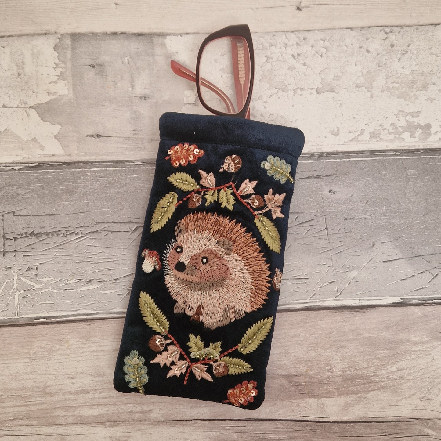 Navy velvet glasses case decorated with an embroidered Hedgehog woodland scene. Finished with beads and sequins.