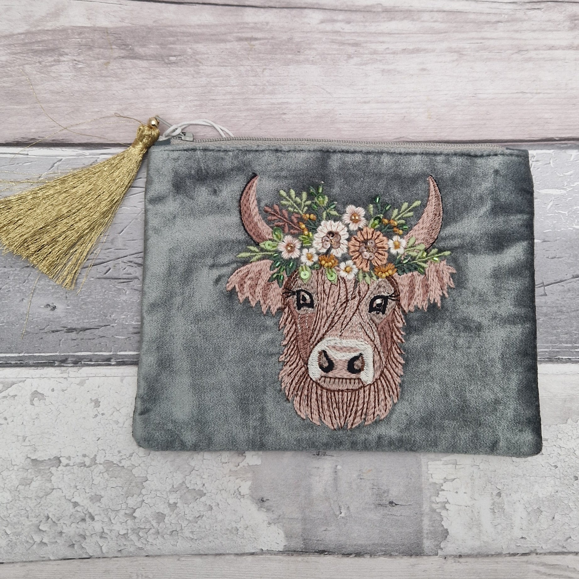 Velvet grey pouch decorated with an embroidered image of a highland cow wearing a crown of flowers. The image is finished with small beads and sequins.