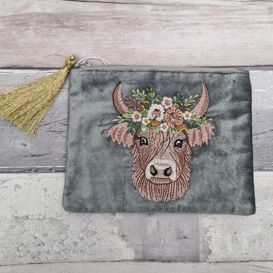 Velvet grey pouch decorated with an embroidered image of a highland cow wearing a crown of flowers. The image is finished with small beads and sequins.