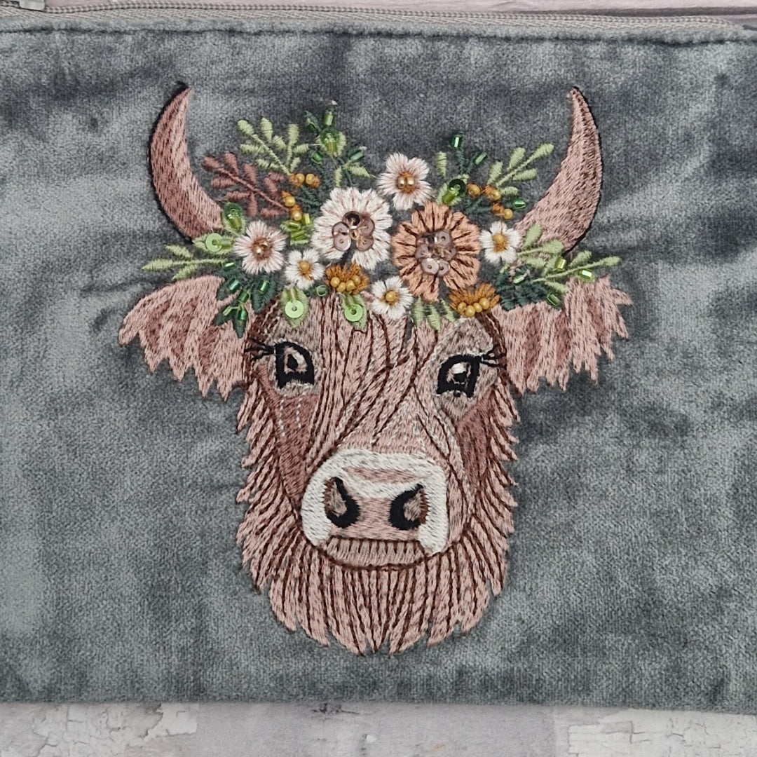Velvet grey pouch decorated with an embroidered image of a highland cow wearing a crown of flowers. The image is finished with small beads and sequins.